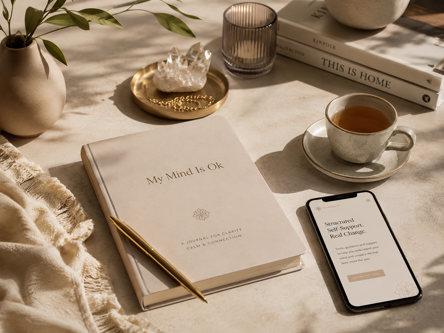 A soft wellness desk flatlay with a notebook, headphones and calming objects